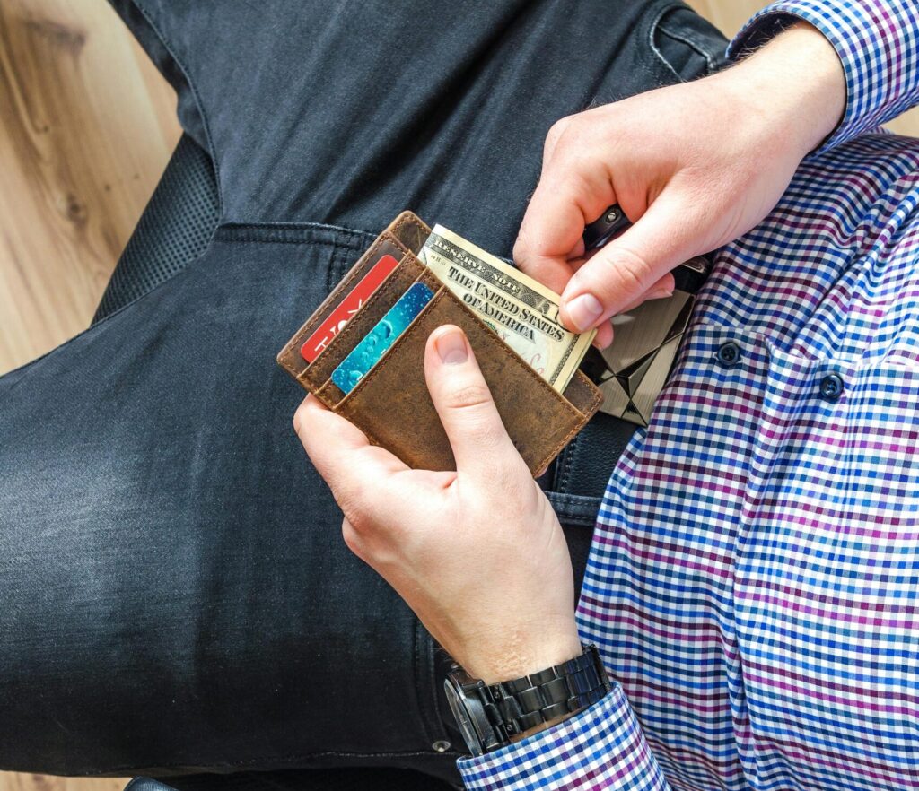 Close-up of a man in casual attire holding a wallet and checking his credit cards indoors.